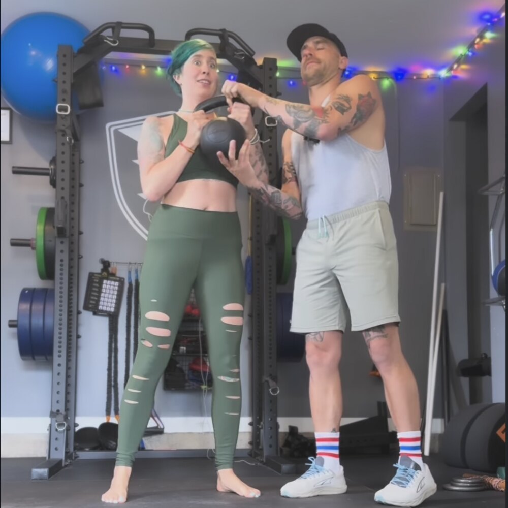 A No Easy Feet coach spotting a client on a kettlebell in the home gym